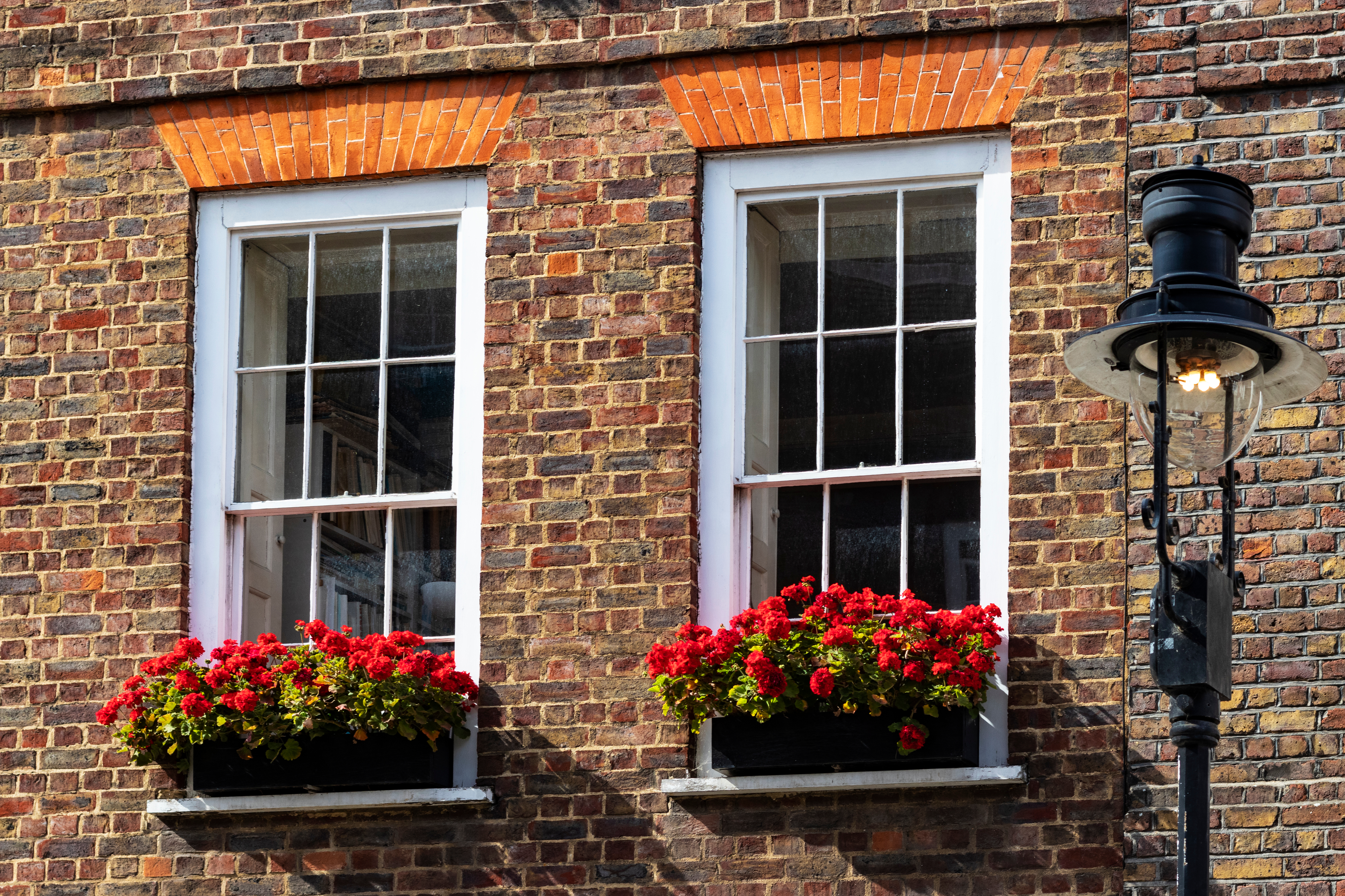 two sash windows in a brick building, red flowerboxes below the windows